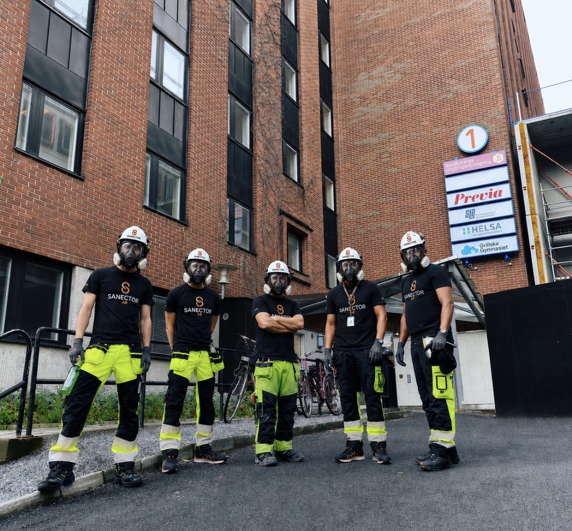 Sanektors team i full skyddsutrustning framför en arbetsplats
